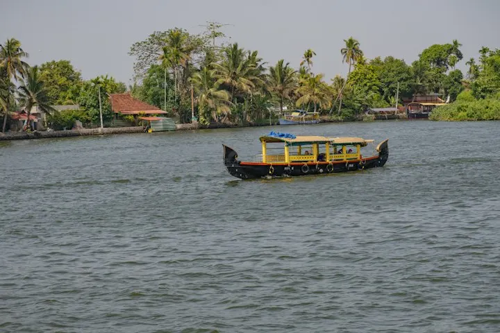 A traditional houseboat sails on a calm river: Alleppey (Alappuzha) holiday packages by OYG Holidays