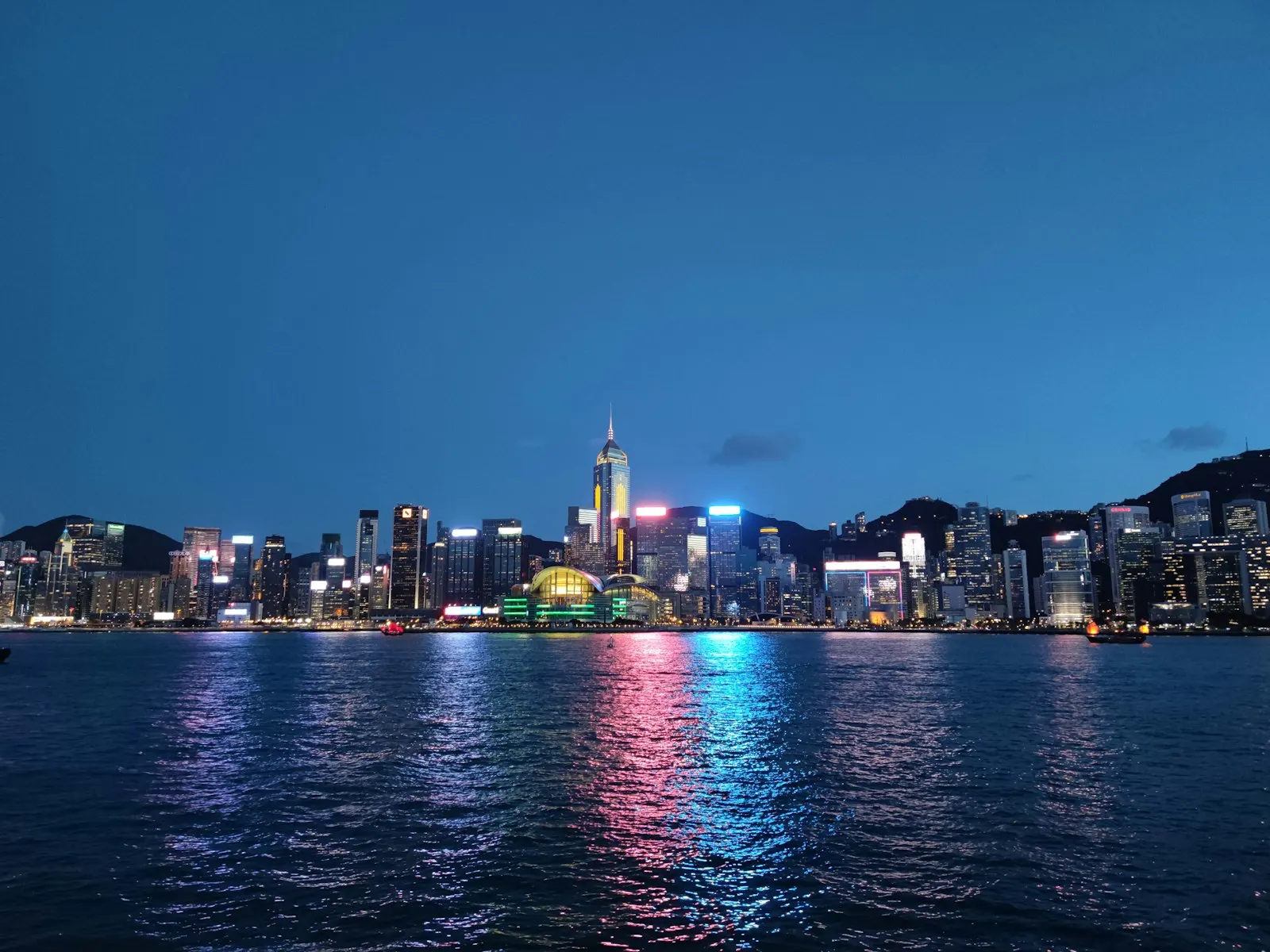 City skyline across body of water during night time The typical and iconic night scenery of the harbor front of Wanchai on H.K.Island, with Central Plaza (the t