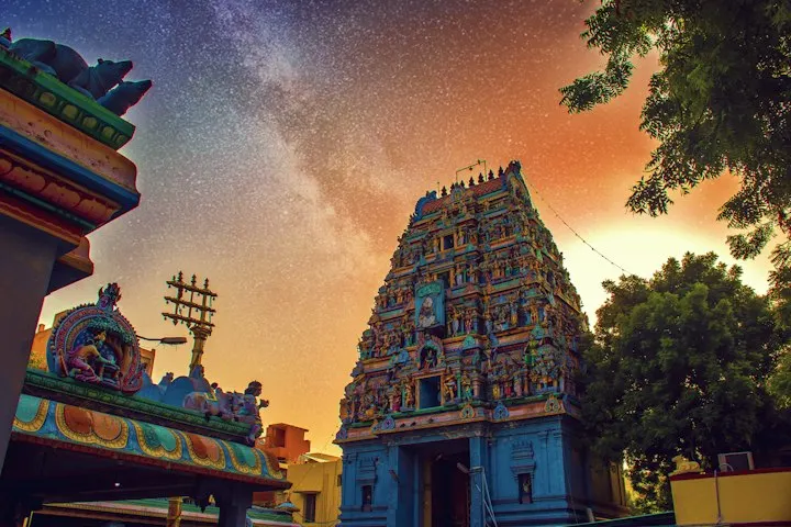A colorful Hindu temple tower beneath a starry night sky with orange light Temple, Tradition, goodvibes, love, peace, god, goddes : Madurai and Rameswaram holid