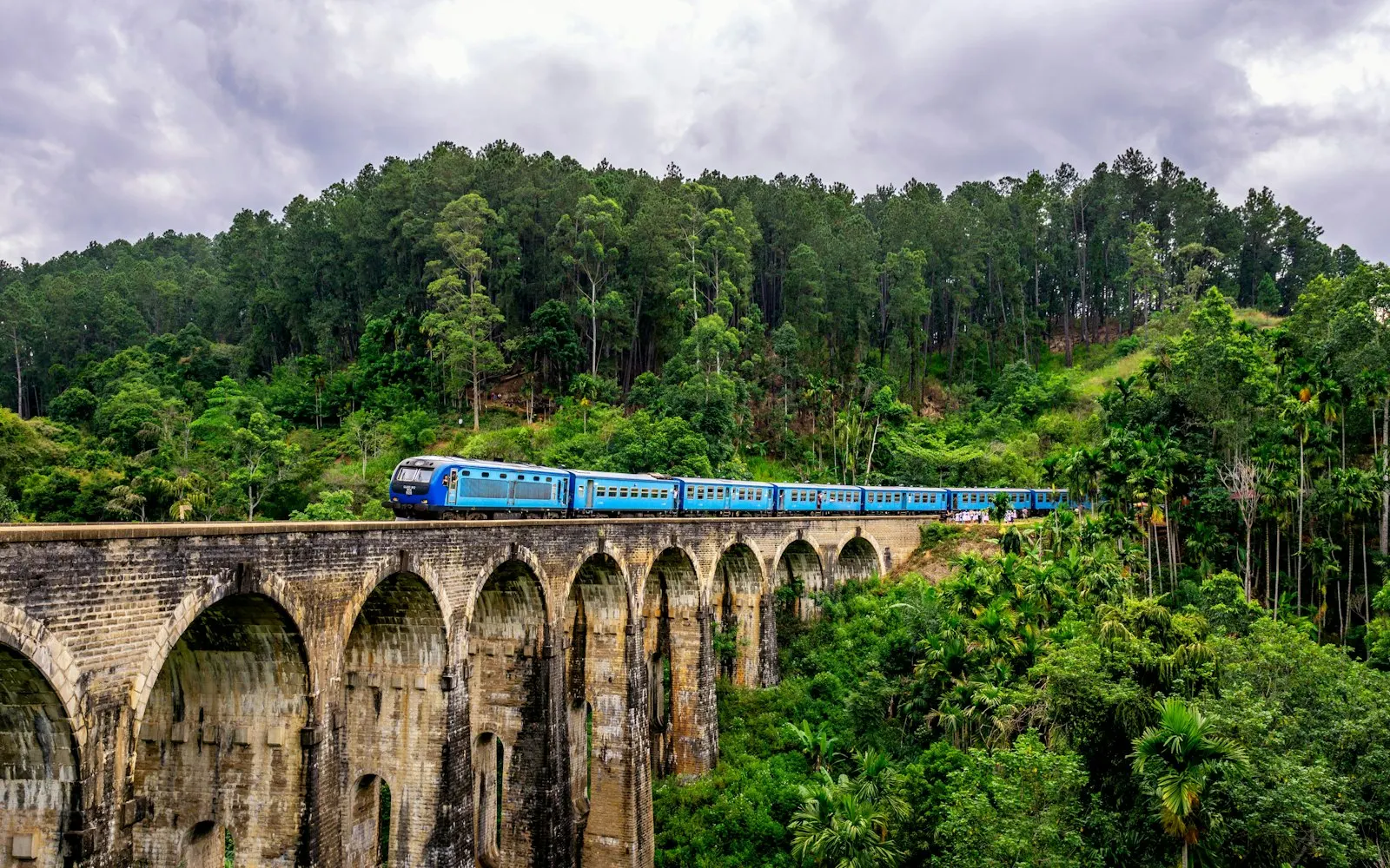 A blue train crossing the Nine Arches Bridge in Ella, Sri Lanka Nine Arches Bridge, Ella, Sri Lanka: Sri Lanka holiday packages by OYG Holidays
