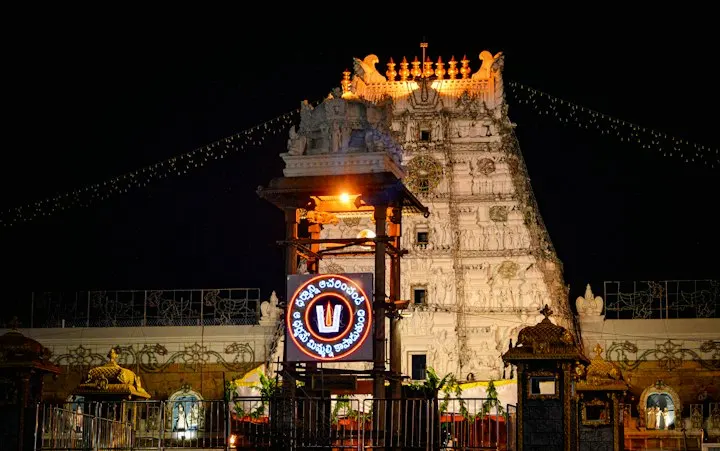 The illuminated gopuram of the Tirumala Venkateswara Temple at night in Tirupati A vibrant night view of a famous Indian temple with a glowing entrance, festive