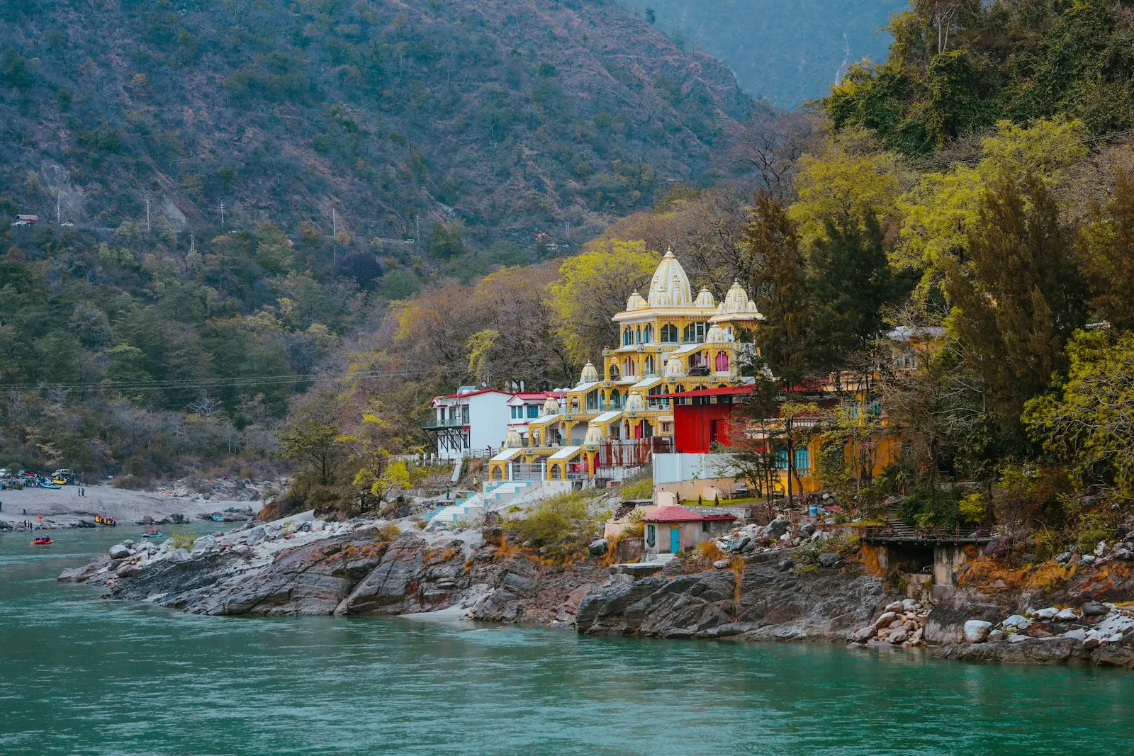 A large building on the side of a mountain next to a body of water: Uttarakhand and Rishikesh holiday packages by OYG Holidays
